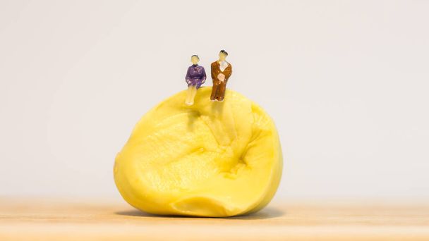 Miniatuur mensen: Mannen en vrouwen zitten op durian geïsoleerd op witte achtergrond  - Foto, afbeelding