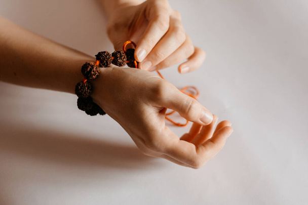 Βραχιόλι από χάντρες Rudraksha στο γυναικείο χέρι προσευχής, close up - Φωτογραφία, εικόνα