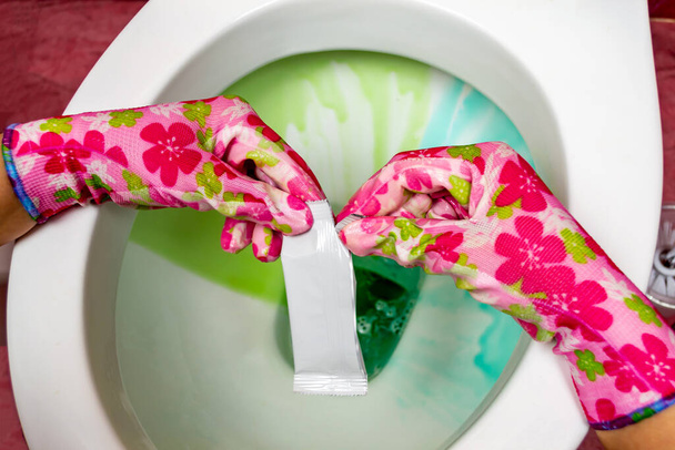 La main d'une femme dans un gant en caoutchouc nettoie la cuvette de toilette avec une brosse, lavabo Nettoyez votre maison. - Photo, image