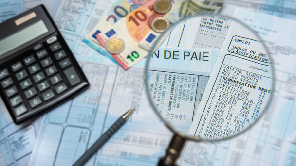 French payroll with a magnifying glass, with euro cash, calculator and pen - Photo, Image