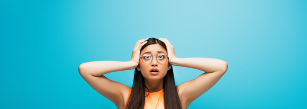 Панорамная концепция азиатской женщины в очках, касающихся головы на голубом - Фото, изображение