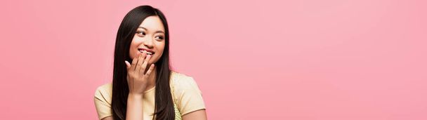 site tête de heureux jeune asiatique femme couvrant bouche isolé sur rose  - Photo, image