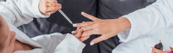 cropped view of girl with nail file making manicure to mother, horizontal image - Valokuva, kuva