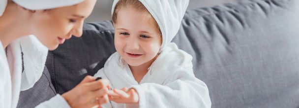 selective focus of mother making manicure to daughter in white bathrobe and towel on head - Foto, Bild