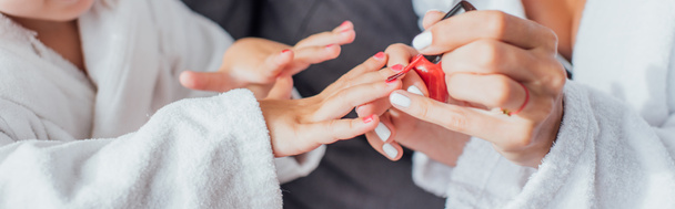 καλλιεργημένη άποψη της γυναίκας που καλύπτει τα νύχια της κόρης με κόκκινο σμάλτο, οριζόντια εικόνα - Φωτογραφία, εικόνα