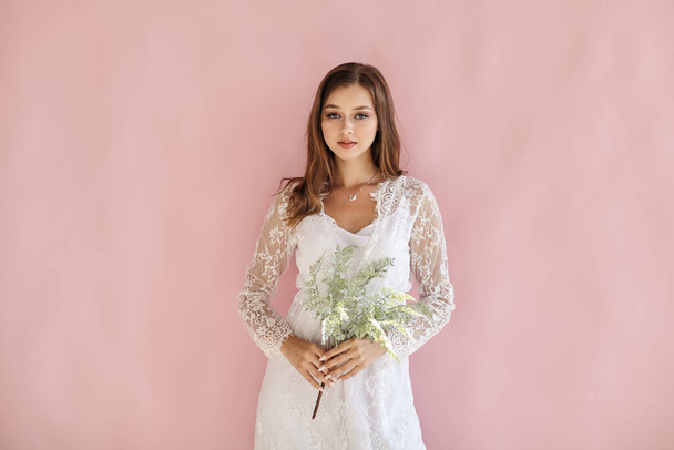 Girl on a pink background holding a green bouquet - Photo, Image
