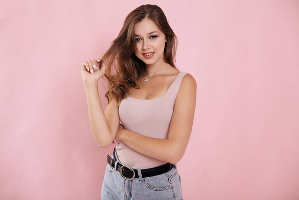 Girl on a pink background holding hair in her hands - Photo, image