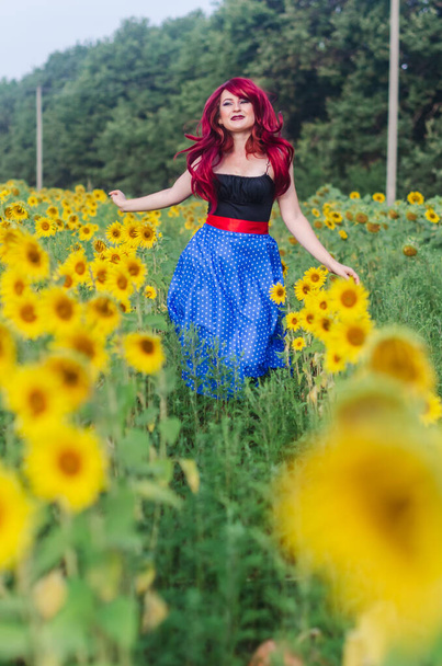 自由の女が畑を歩く。平和と静けさは人の喜びを満たす。赤いウィッグ長い青いスカート - 写真・画像