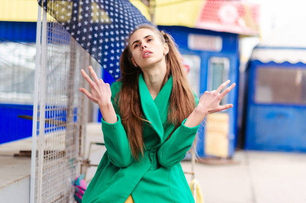 young girl teenager, dressed in a green coat, bright and cheerful.  holidays for schoolchildren.  on the face of emotions, discontent, question, anger. - Foto, imagen