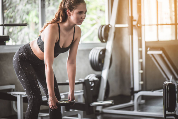 Cinematic tone of young attractive fitness woman exercise with machine and dumbbell in gym. Individual sport to fit muscles of body for healthy life concept. - Foto, Imagem