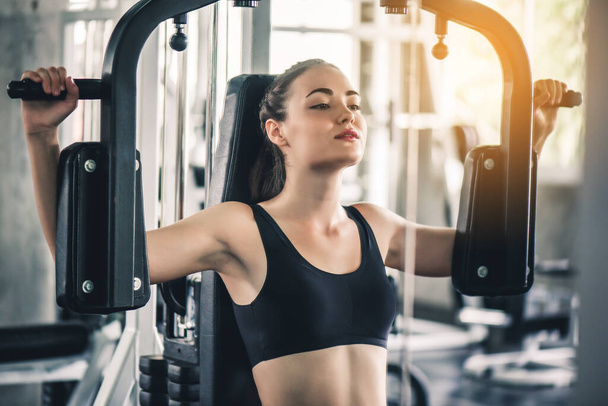 Cinematic tone of young attractive fitness woman exercise with machine in gym. Individual sport to fit muscles of body for healthy life concept.  - Photo, Image