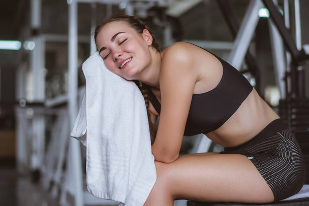 Young attractive using towel to wipe the sweat. Relaxation after hard workout in gym.  - Valokuva, kuva
