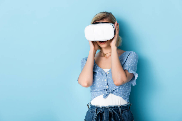 young woman touching virtual reality headset on blue  - Photo, Image