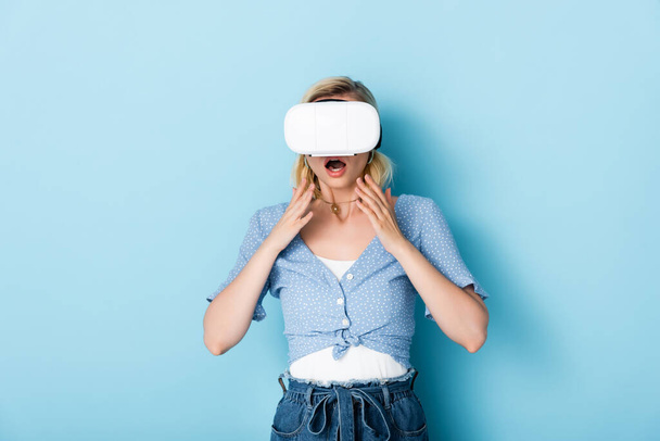 young and shocked woman in virtual reality headset on blue  - Foto, imagen