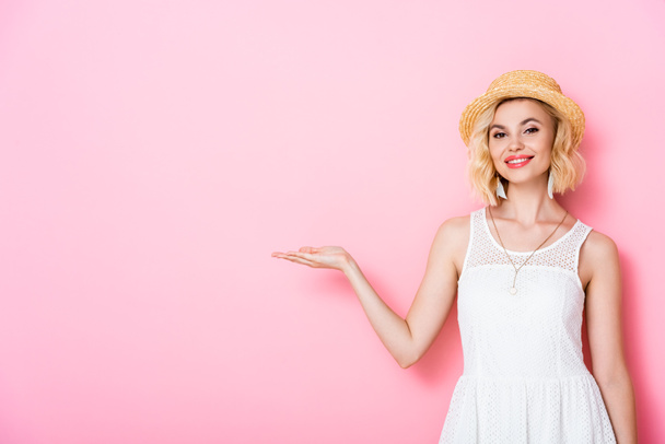 woman in straw hat pointing with hand on pink  - Foto, Bild
