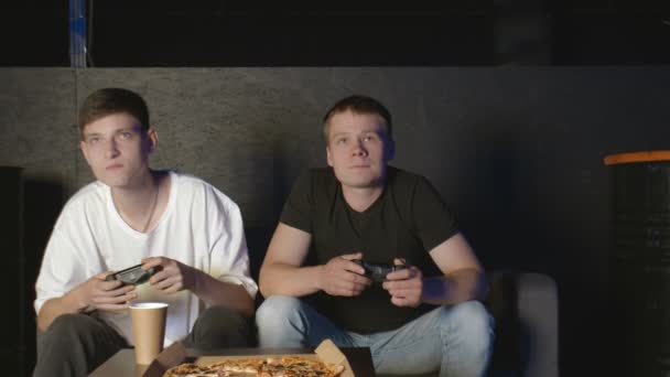 Ευτυχισμένοι δύο φίλοι απολαμβάνουν χαλάρωση παίζοντας βιντεοπαιχνίδια και διασκεδάζοντας σε εσωτερικούς χώρους - Πλάνα, βίντεο