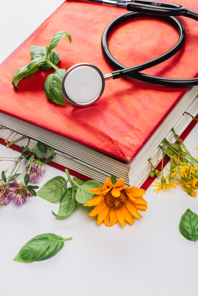 herbs in book with stethoscope on white background, naturopathy concept - Φωτογραφία, εικόνα