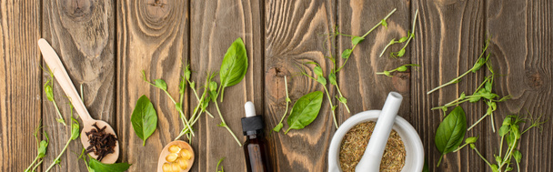 vista superior de pílulas em colheres, argamassa, ervas verdes e garrafa na superfície de madeira, conceito de naturopatia
 - Foto, Imagem
