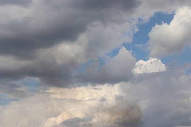 op de blauwe lucht witte en grijze wolken, een prop grijze rook op de achtergrond van wolken - Foto, afbeelding