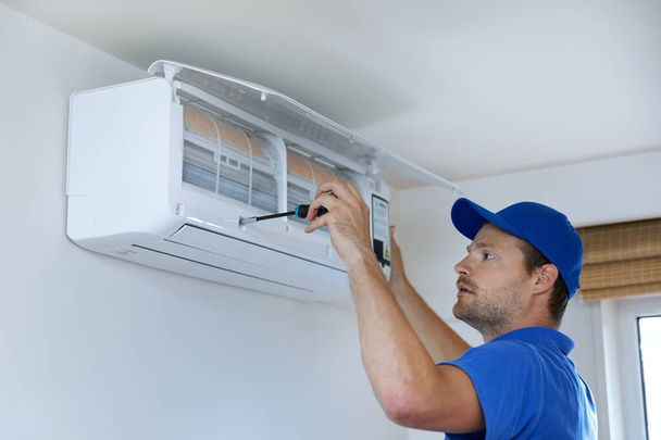 hvac services - monteur installeren van airconditioner aan de muur thuis - Foto, afbeelding