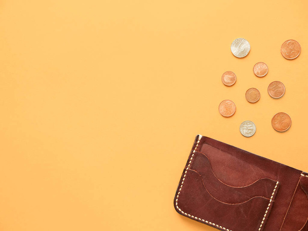 brown wallet with with scattered dollar and euro coins on yellow background. last money, poverty, unemployment, job loss, saving concept. Flat lay, copyspace. - Foto, Imagen
