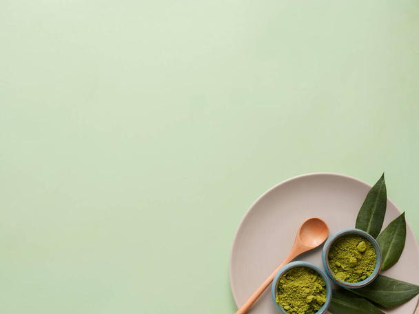 matcha tea on grey plate with spoon and leaf on grean background. Concept healthy drink, copyspace, flatlay, top view. - Fotó, kép