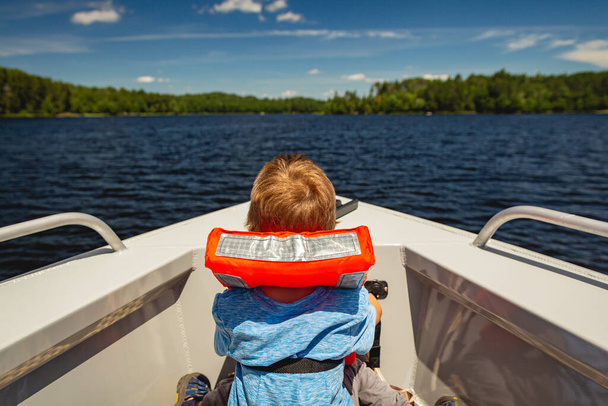 Junge reitet im Bug eines Bootes auf dem Kabetogama-See im Voyageurs National Park, Minnesota - Foto, Bild