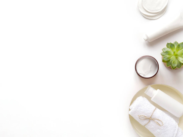 care products cream, lotion, cotton pads, plant, towel. bath accessories on white background, top view, copyspace. Bodycare beauty treatments concept, organic bath products, morning routine. - 写真・画像