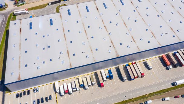 Vista aérea del almacén de mercancías. Centro logístico en zona industrial de ciudad desde arriba. Vista aérea de camiones cargando en el centro logístico foto de stock
 - Foto, imagen