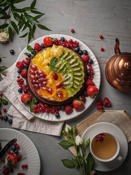Meyveli kek fotoğrafçılığı. Meyve ve meyveli turta. Tabakta çay fincanı ile gri desenli masa, üst manzara. - Fotoğraf, Görsel