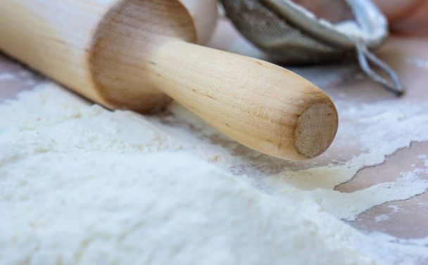 Baking tools and ingredients - flour, rolling pin, eggs, parchment. View from above. Home cooking concept rustic background - Photo, Image