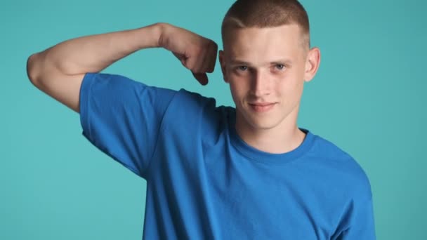 Attractive strong guy happily showing biceps muscles on camera over colorful background. Power expression - Footage, Video