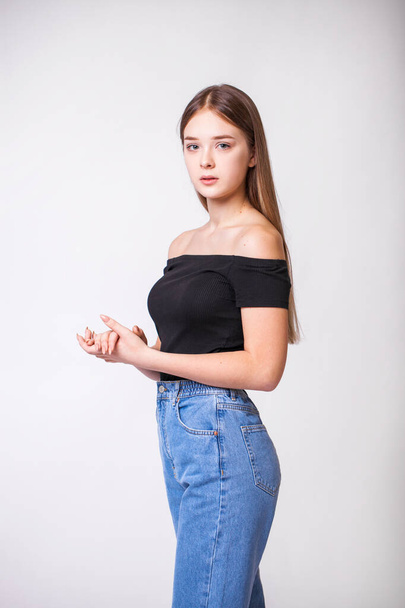 Closeup portrait of a young beautiful girl in blue jeans - isolated on gray background - Φωτογραφία, εικόνα