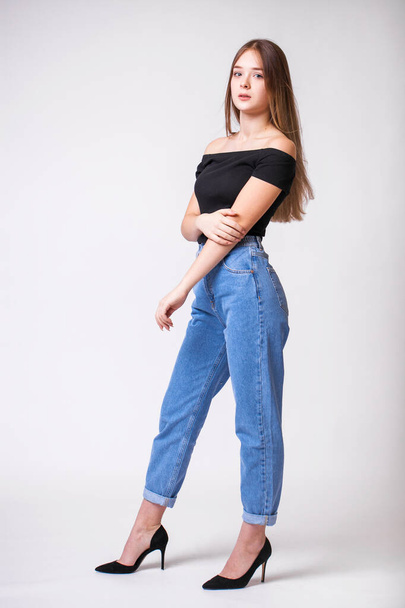 Beautiful sexy brunette woman in blue jeans. Fashion model in jeans clothing. Isolated on gray studio background - Photo, Image
