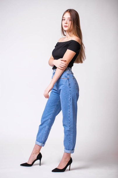 Beautiful sexy brunette woman in blue jeans. Fashion model in jeans clothing. Isolated on gray studio background - Zdjęcie, obraz