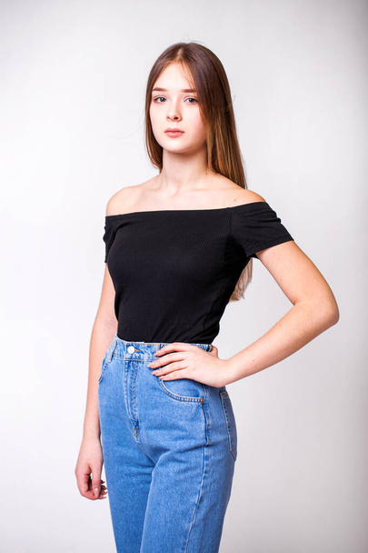 Closeup portrait of a young beautiful girl in blue jeans - isolated on gray background - Fotó, kép