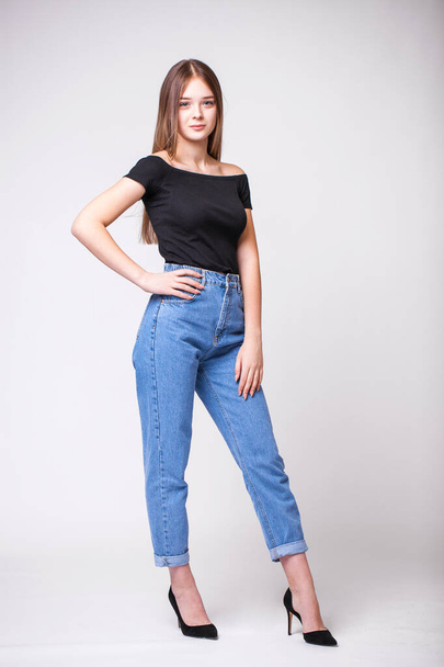 Beautiful sexy brunette woman in blue jeans. Fashion model in jeans clothing. Isolated on gray studio background - Fotoğraf, Görsel
