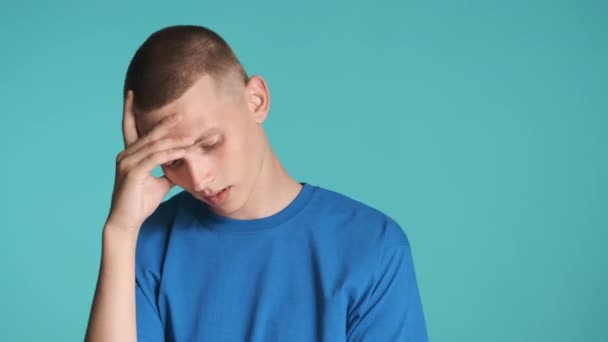 Jonge man met blauwe ogen die schuldig gezicht bedekt met de hand over kleurrijke achtergrond. Gezichtsuitdrukking - Video