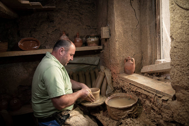 Muž hrnčíř dělá hrnec na hrnčířském kole. Terakotový keramik na točícím se kole. Muži dělat nápady o keramice s centrem země - Fotografie, Obrázek