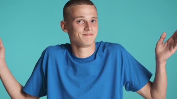 Young casual blue eyed man throwing up hands on camera over colorful background. I don't know expression - Footage, Video