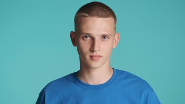 Portrét pohledné modré oči blond chlap upřeně dívá do kamery přes barevné pozadí - Záběry, video