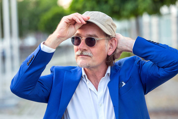 portrait of handsome businessman in his 50s with sunglasses fixing his hat - Fotoğraf, Görsel