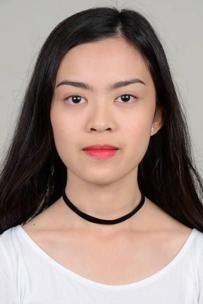 Estudio disparo de joven hermosa mujer asiática sobre fondo gris
 - Foto, imagen