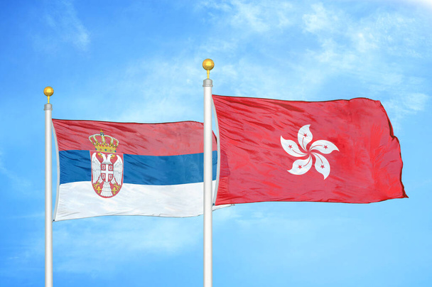 Serbia y Hong Kong dos banderas sobre asta de bandera y fondo azul cielo nublado - Foto, Imagen