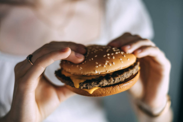 Female hands holding delicious fresh cheesburger. close-up. High quality photo - Foto, afbeelding