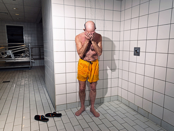 Un aîné prend une douche dans la salle de bain. Porter une natation jaune
 - Photo, image