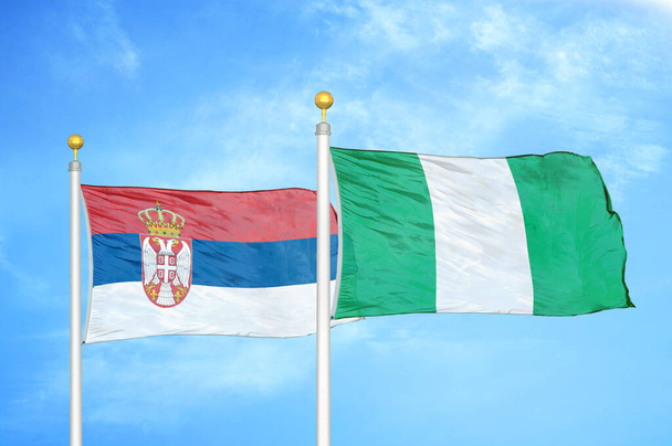 Serbien und Nigeria zwei Flaggen auf Fahnenmasten und blauer bewölkter Himmel Hintergrund - Foto, Bild