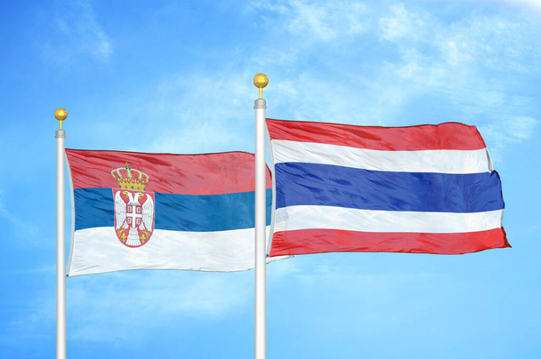 Serbia y Tailandia dos banderas sobre asta de bandera y fondo azul cielo nublado - Foto, Imagen