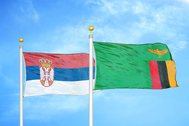 Serbia y Zambia dos banderas sobre asta de bandera y fondo azul cielo nublado - Foto, Imagen