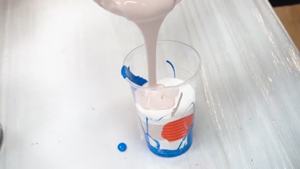 Filmación de la mezcla de pinturas acrílicas en taza de plástico - Metraje, vídeo